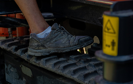 Bota postavená na stejně širokém pásu malé vrtné soupravy uprostřed osazené zahrady.