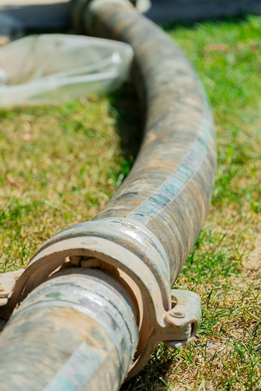 Velká hadice připojená ke stroji při vrtání vrtané studny, která šetrně odvádí vyhloubený materiál mimo pozemek.